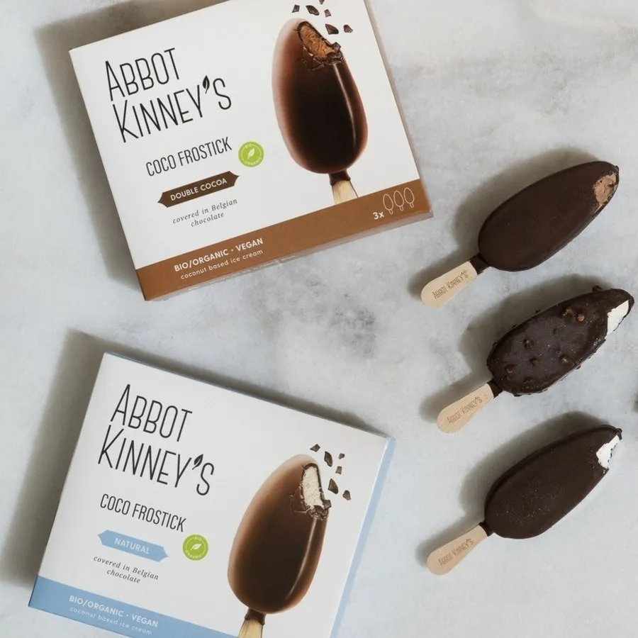 Twee dozen Coco Frostick, Double Cocoa en Natural, naast drie ijsjes op marmer.